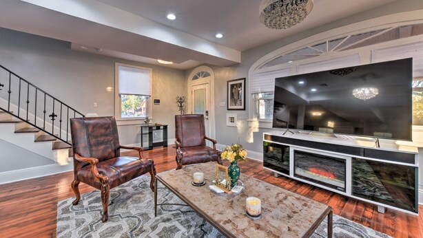 A modern living room with a fireplace, leather chairs, a coffee table with candles, and a staircase. - 3 Mi to French Quarter: Family Home in New Orleans (New Orleans)