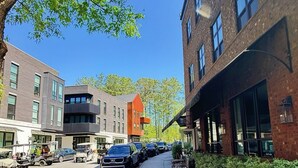 A street view with parked cars, a sidewalk, and buildings with large windows and brick facades. - Serenbe, Palmetto, Ga, Escape, Serenity, Unforgettable, Scenic, Relaxation, New (Palmetto)