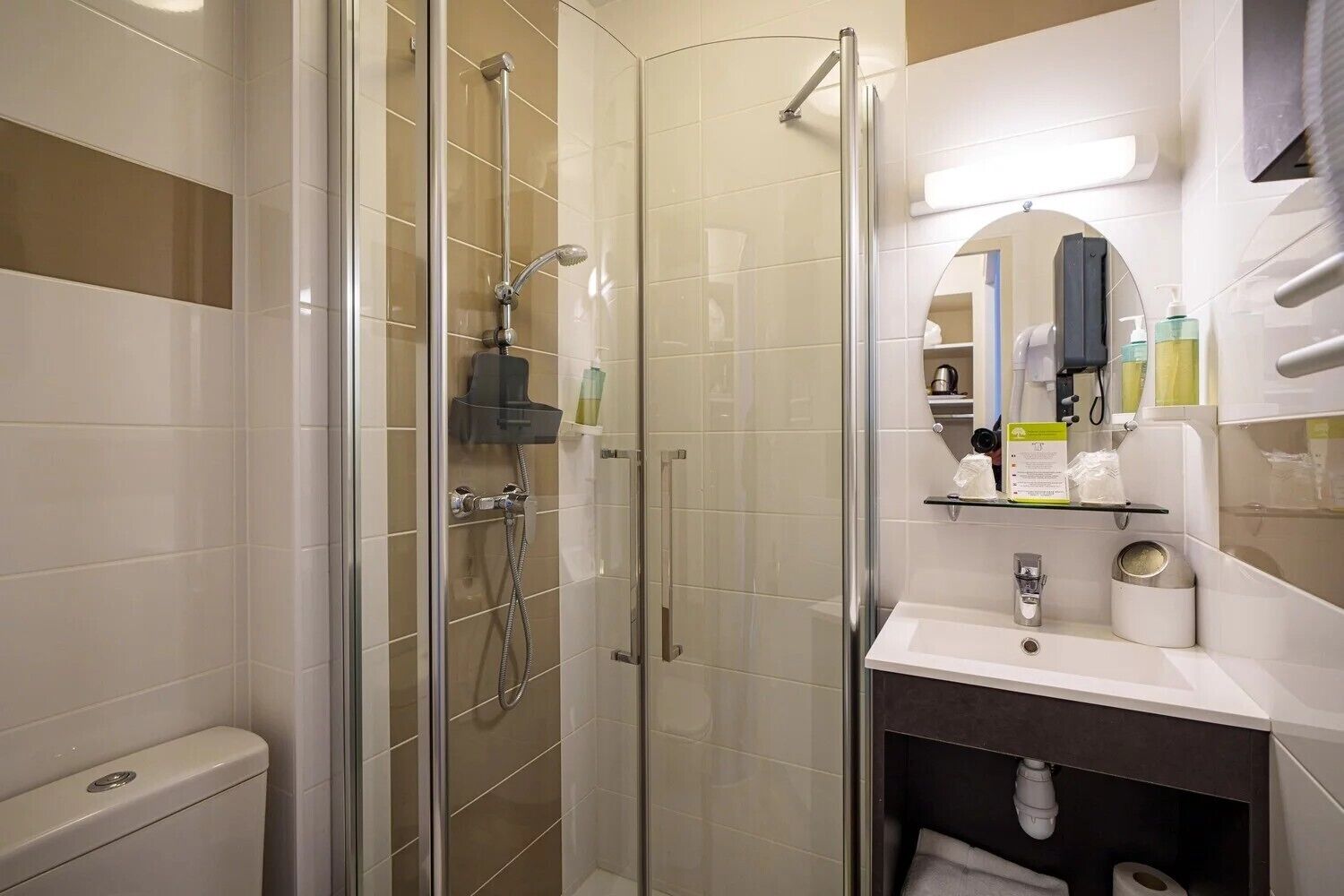 A modern bathroom with a glass-enclosed shower, a white sink with a mirror above it, and a toilet.