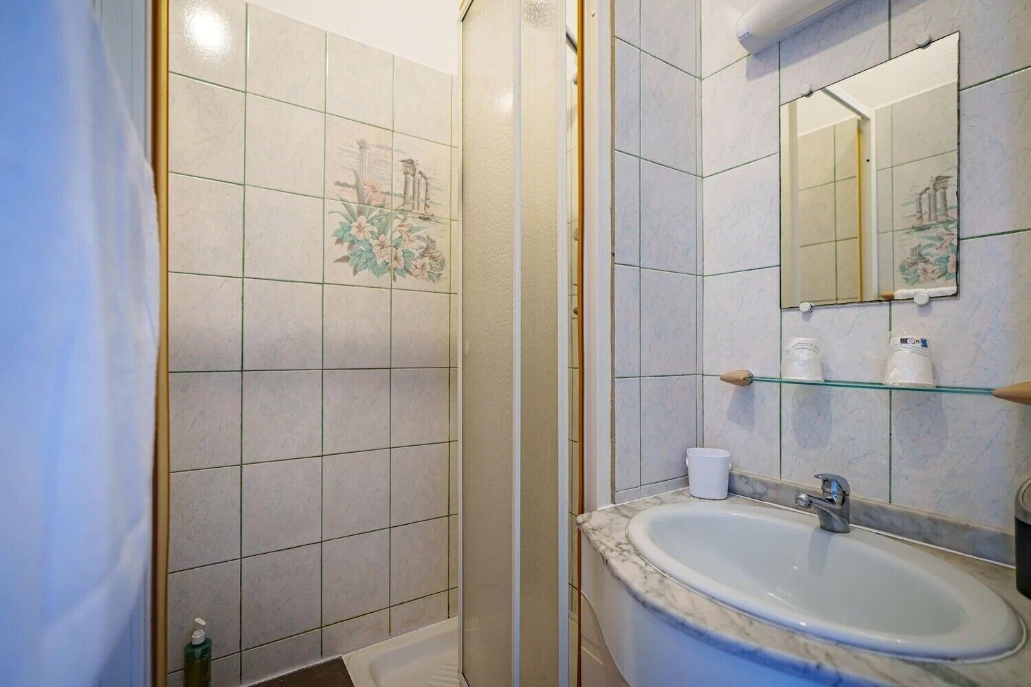 Ein Badezimmer mit Waschbecken, Spiegel und Duschbereich.