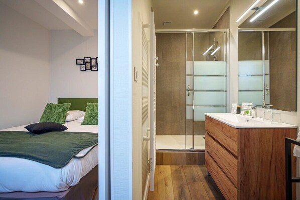 A modern bedroom with a bed, green pillows, a bedside table, and a nightstand. - L'Escale de la Gare (Saumur)