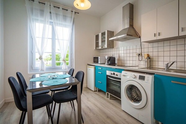 Une cuisine compacte équipée d’un lave-linge, d’un four à micro-ondes et d’un four traditionnel.