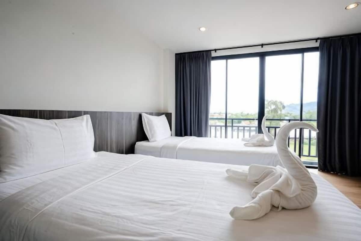 Habitación de hotel con dos camas, un balcón con vistas y una decoración con forma de cisne sobre la cama.
