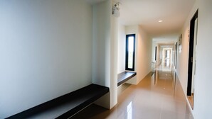 Un couloir moderne et bien éclairé, avec un banc, un projecteur et une porte donnant sur une autre pièce.