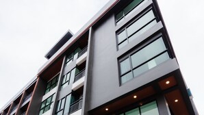 Un immeuble moderne à plusieurs étages, doté de grandes fenêtres, d’un escalier menant à l’entrée et d’un toit plat.