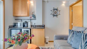 Un espacio habitable compacto con kitchenette, comedor y zona de estar con sofá.