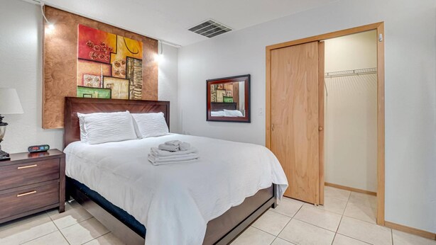 Una habitación de hotel ordenada con cama, mesita de noche y armario.