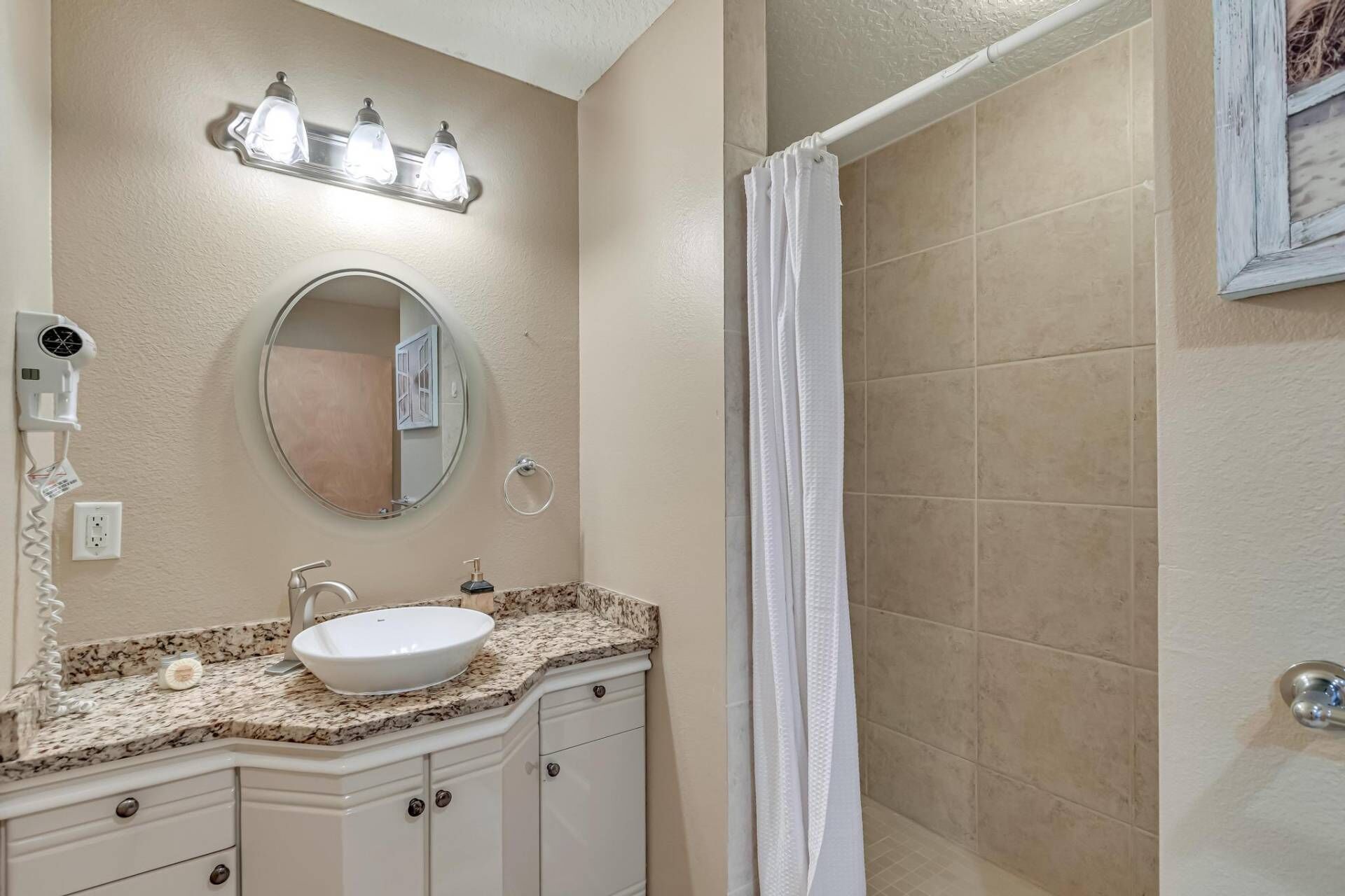 A bathroom with a sink, mirror, and shower curtain.