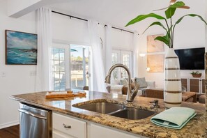 A modern kitchen with granite countertops, stainless steel appliances, and a large window. - Waterside Villa | Canal • Pool • Spa • Kayaks (Palm Coast)