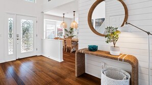 Un intérieur moderne avec un plancher en bois, un miroir rond, une plante en pot et un panier en osier.