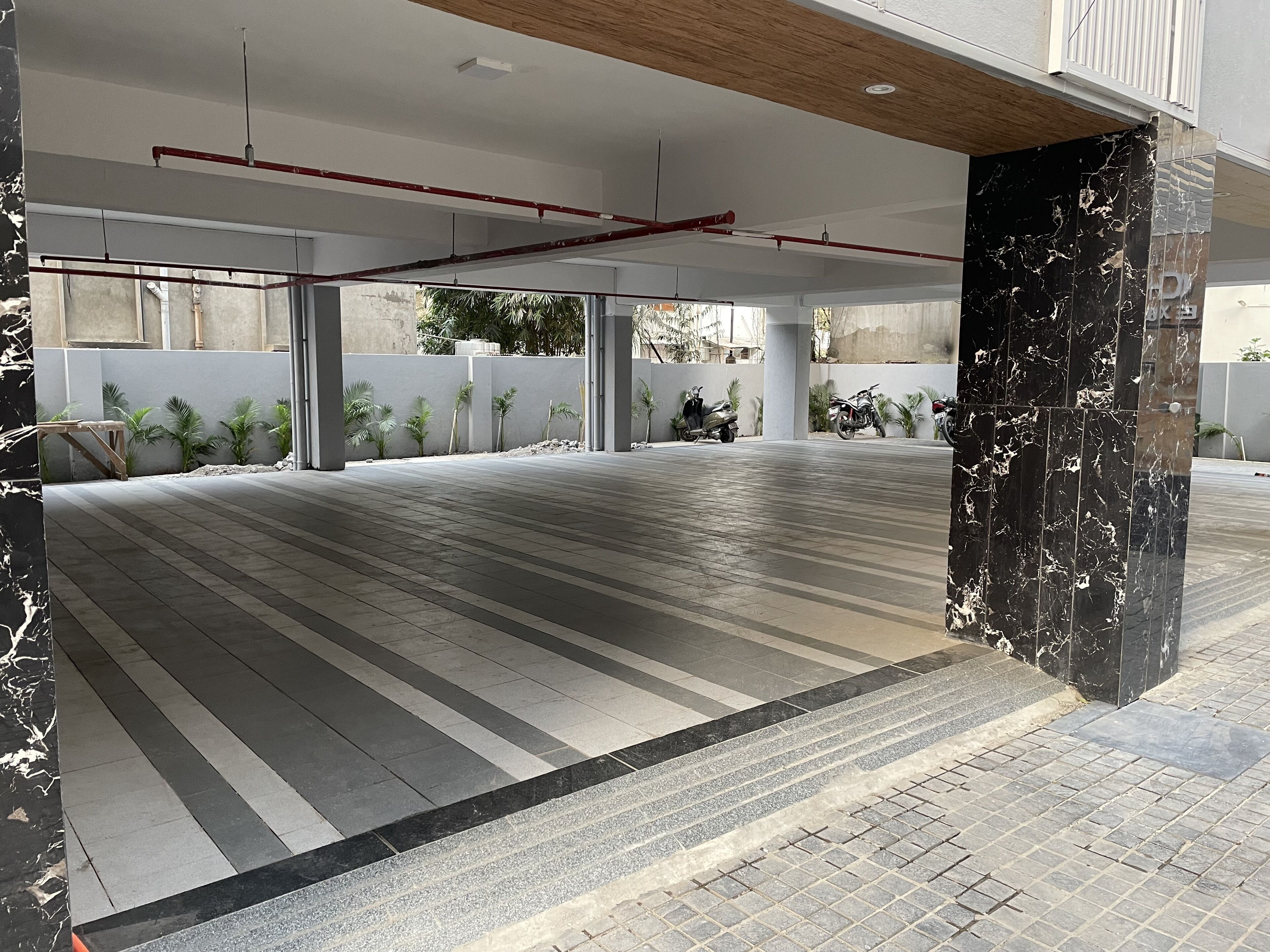 A spacious indoor area with tiled flooring, a wooden ceiling, and a black marble column.