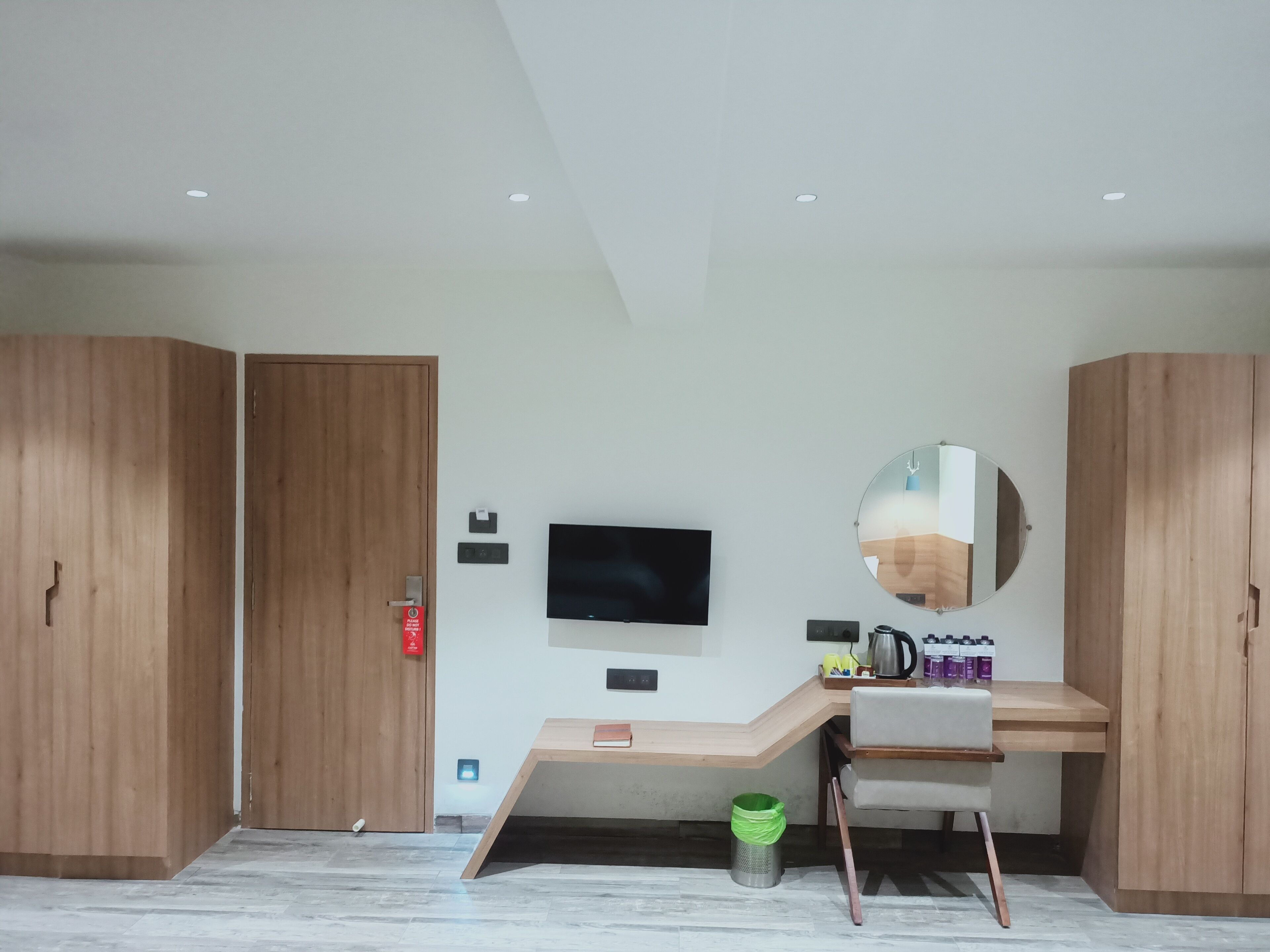 Un dormitorio moderno con armarios de madera, un escritorio con silla, televisor y espejo.