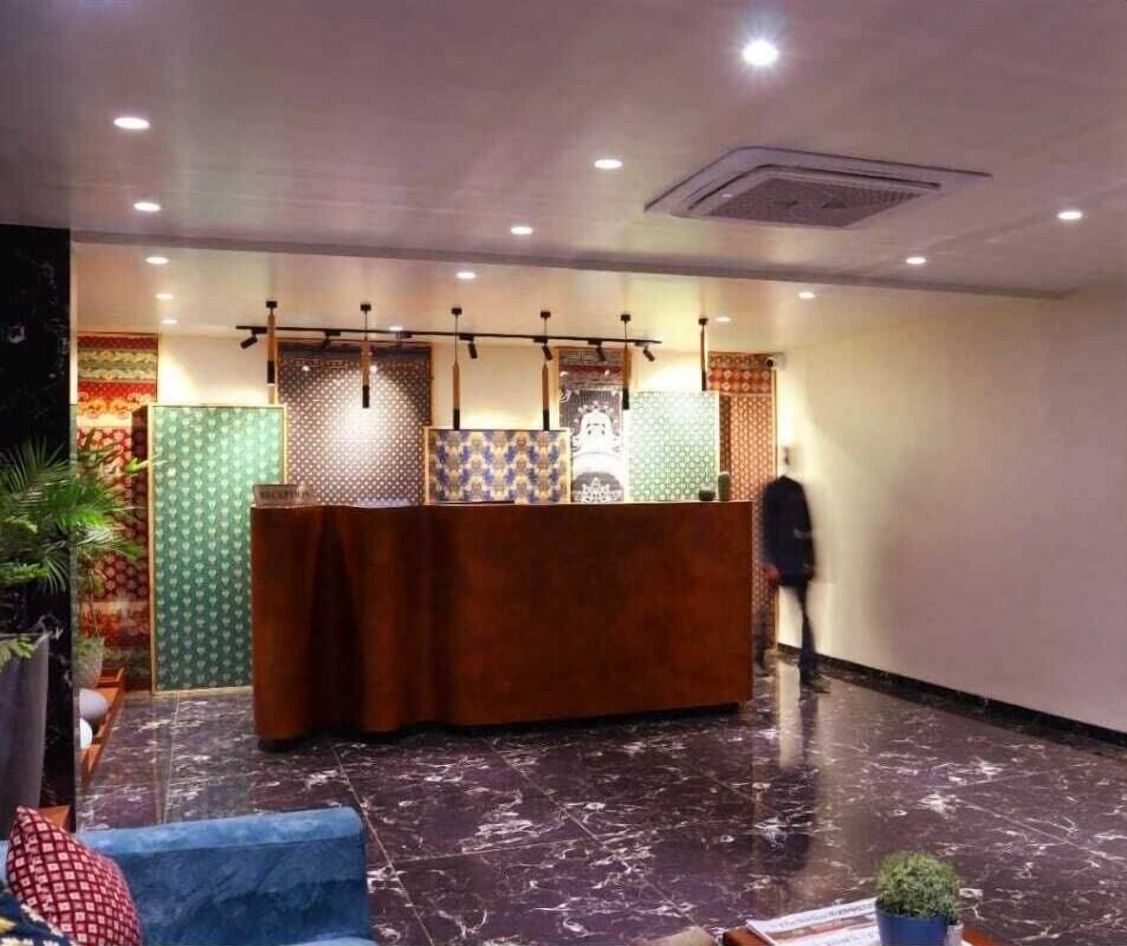 Un'area reception con un bancone in legno, decorazioni parietali a motivi e un pavimento in marmo.