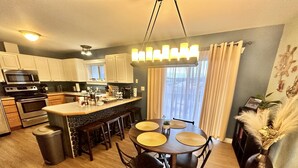 A modern kitchen with a central island, stainless steel appliances, and a dining area with a round table and chairs.
