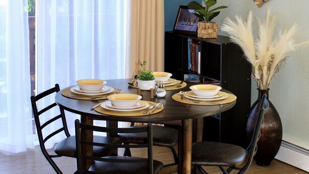 A dining area with a round table, chairs, and a chandelier.