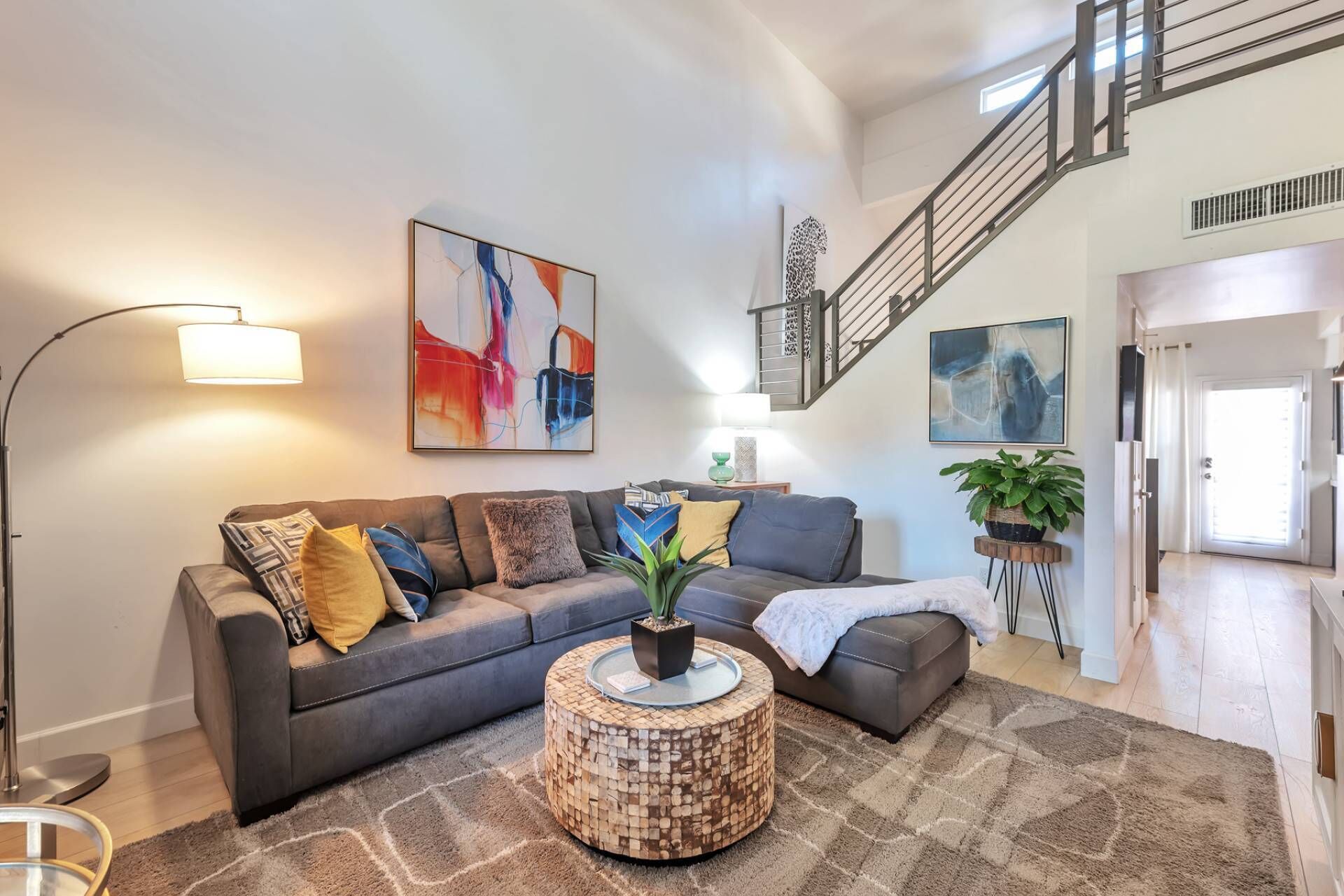 A modern living room with a grey sofa, a round coffee table, and abstract art on the walls.
