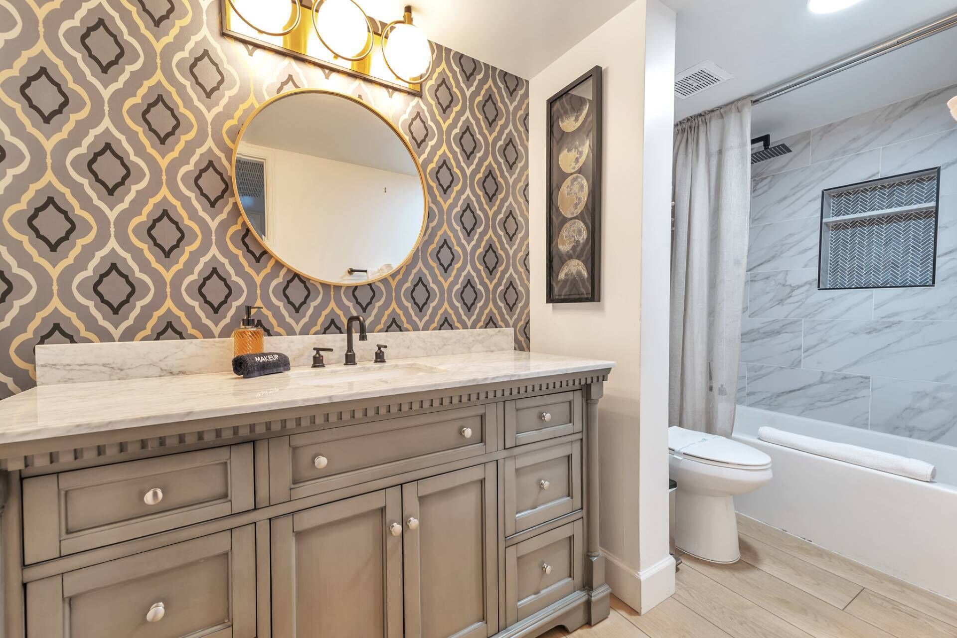A bathroom with a vanity, sink, and mirror. There is a shower area with a glass door and a toilet.