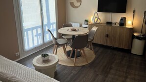 Ein modernes Wohnzimmer mit einem runden Esstisch, bequemen Sitzmöglichkeiten, einem Flachbildfernseher und einem Balkon mit Aussicht.
