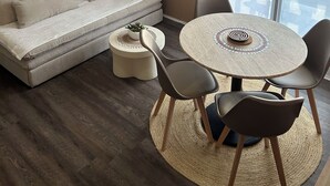 Ein modernes Wohnzimmer mit einer Couch, einem runden Tisch mit Stühlen, einem Deckenventilator und einem großen Fenster.