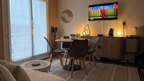 Ein modernes Wohnzimmer mit Fernseher, Essbereich und Sofa.
