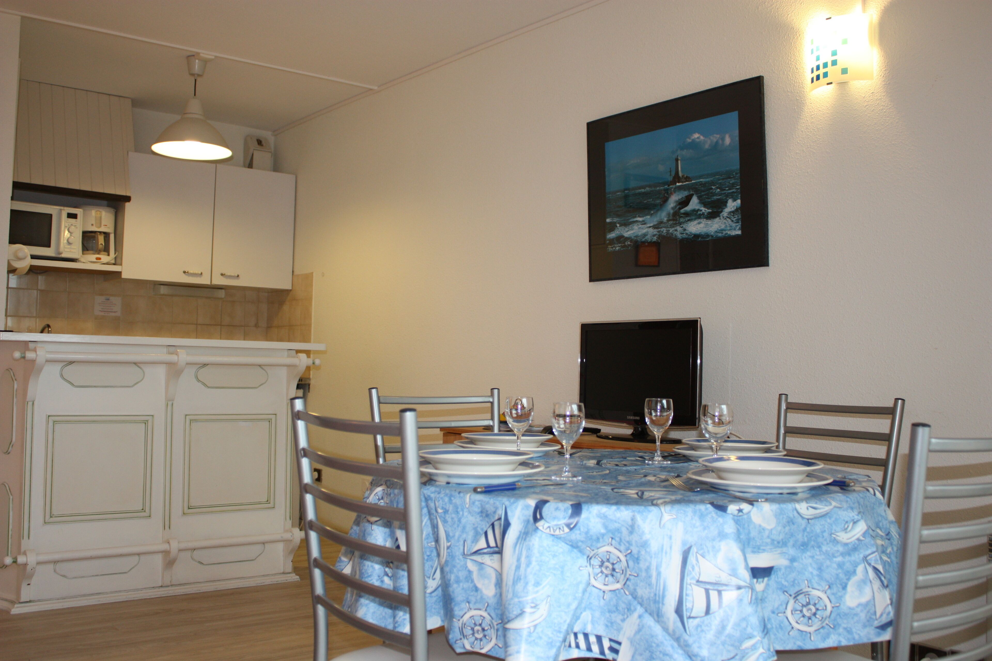 Un coin repas avec une table dressée pour quatre personnes, comprenant des assiettes, des verres et des couverts.