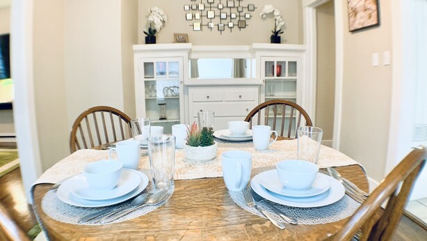 A dining area with a round wooden table set for four, surrounded by wooden chairs.