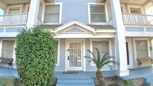 A two-story house with a front porch, a small garden, and a bench.