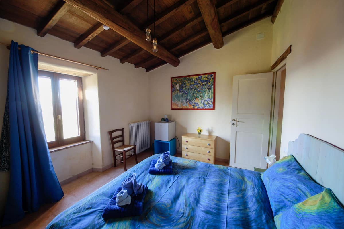 Ein Schlafzimmer mit Bett, Stuhl, Kommode, Heizkörper und einem Bild an der Wand.