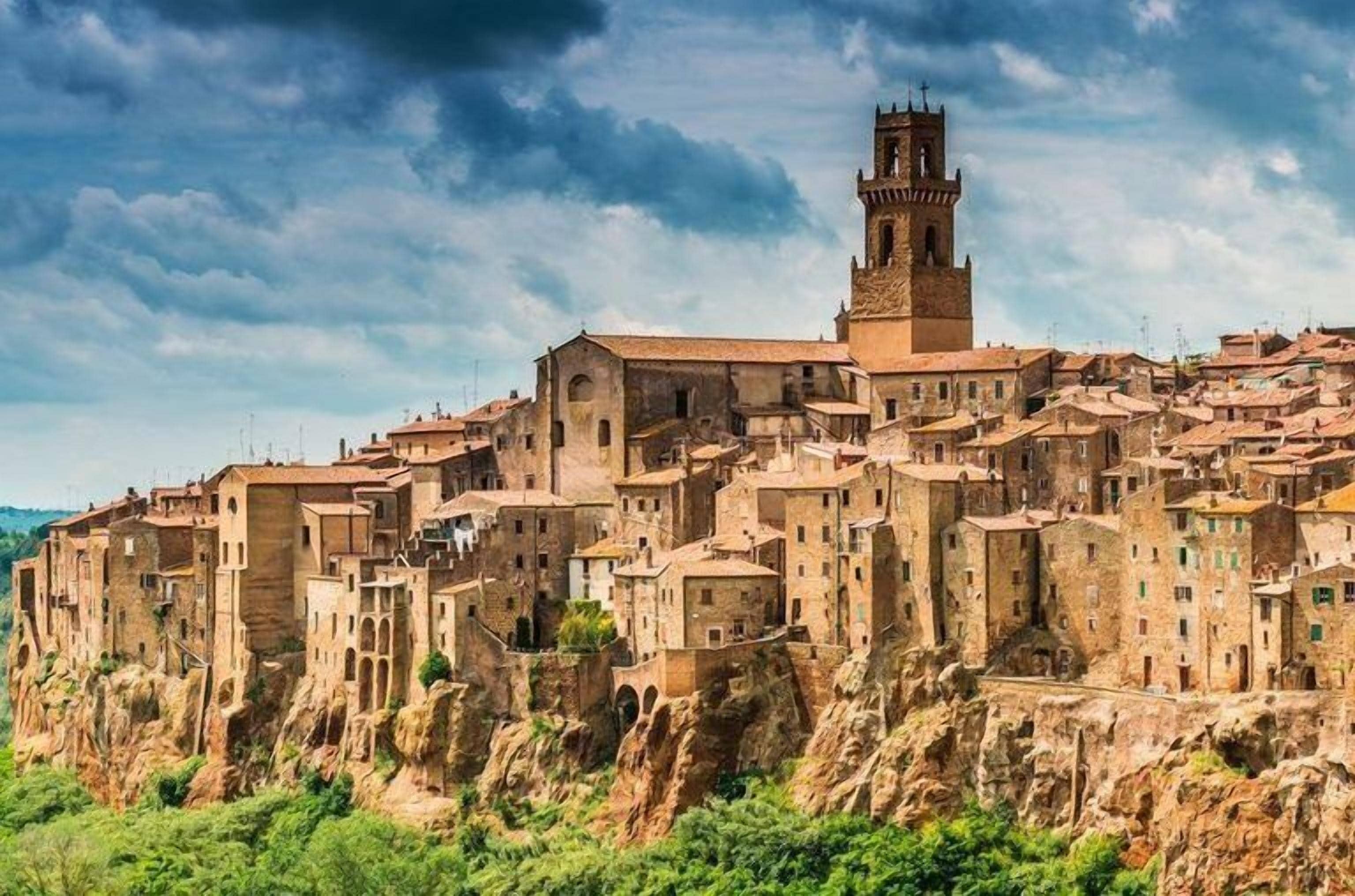 Une ville historique construite sur une falaise, avec des bâtiments traditionnels en pierre et un clocher d’église imposant.