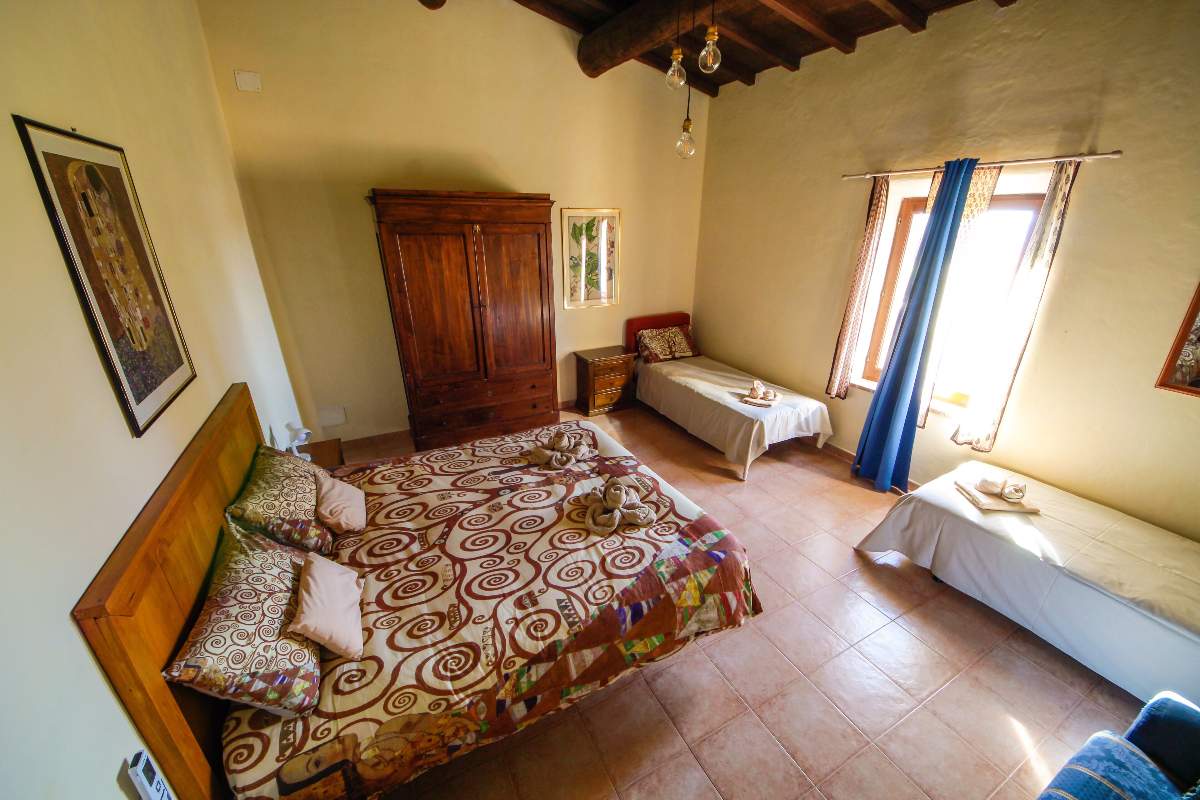 Un dormitorio con una cama grande, una cama más pequeña, un armario y una ventana con cortinas.