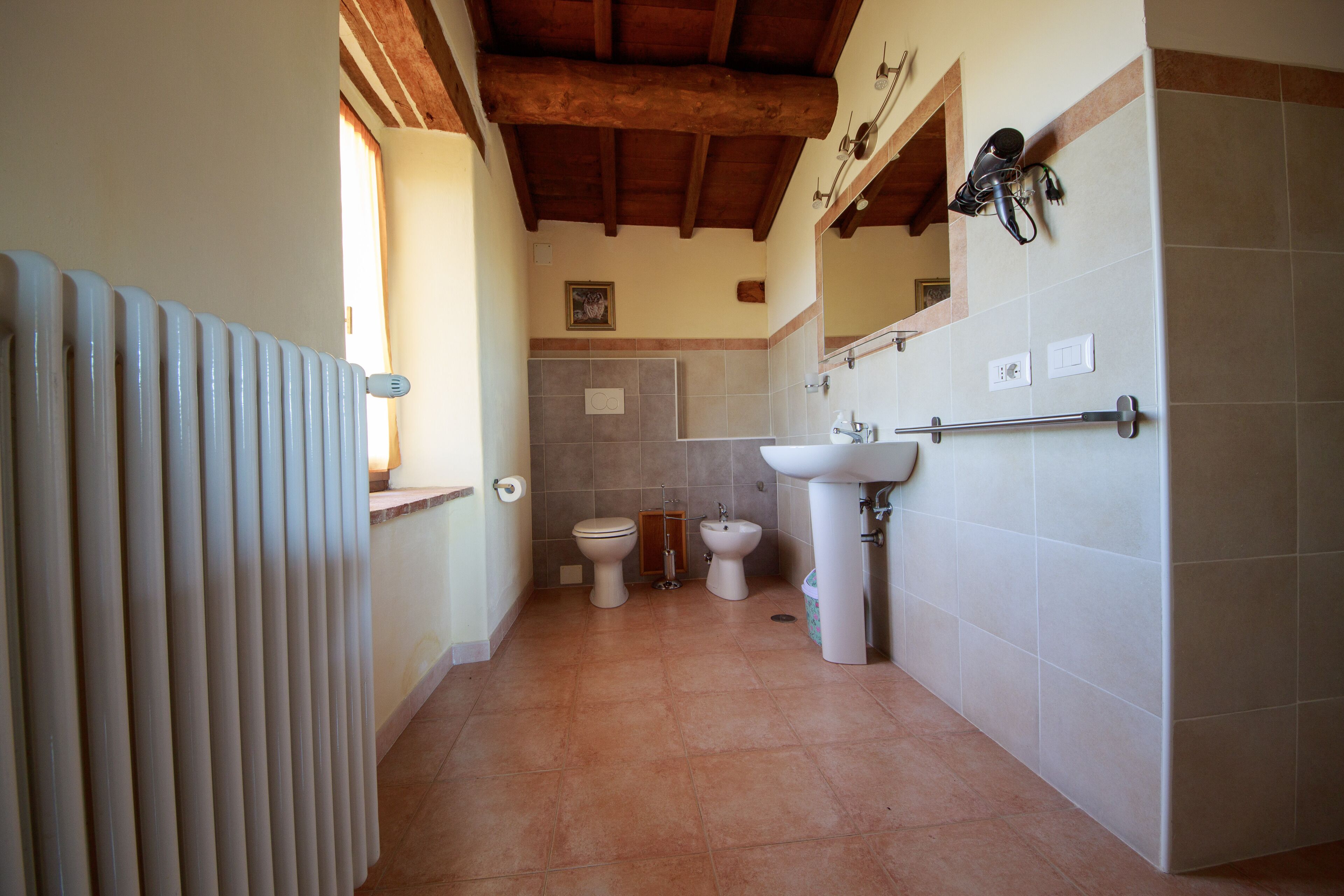 A bathroom with a radiator, a toilet, a bidet, and a sink.