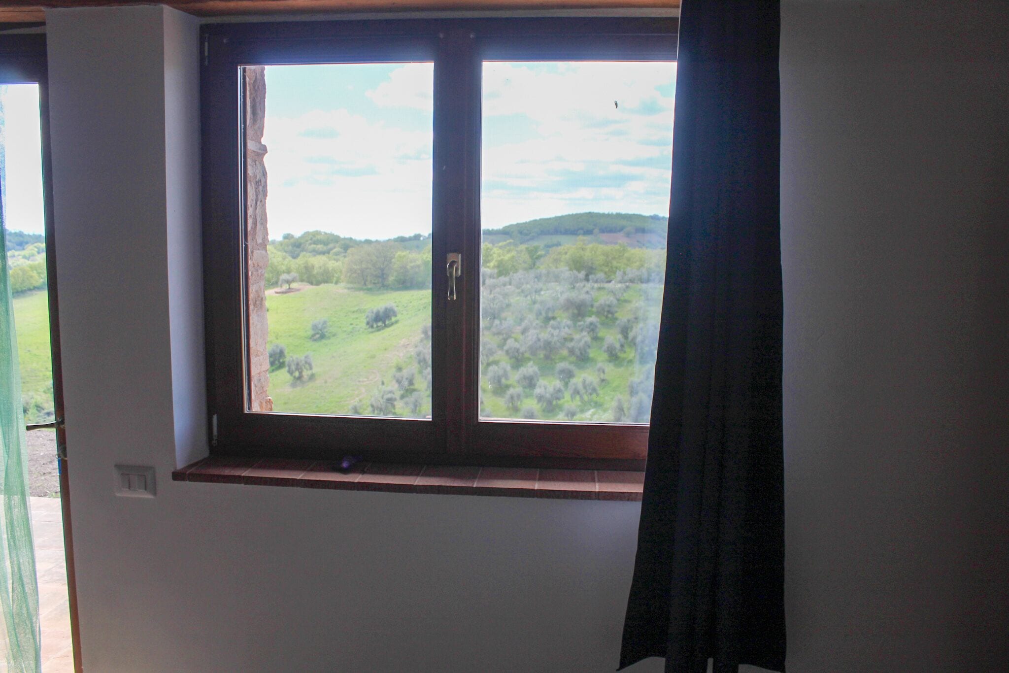 A room with a window overlooking a green landscape.