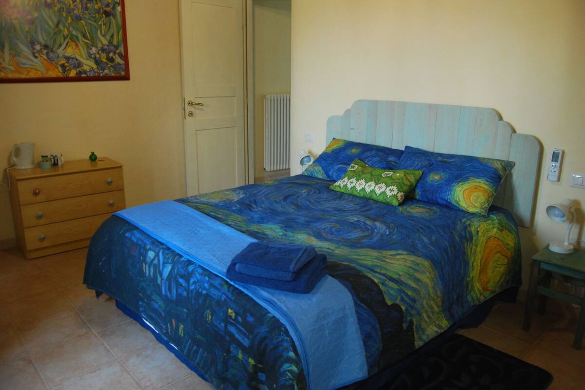 Ein Schlafzimmer mit Bett, Schminktisch, Nachttisch und einem Bild an der Wand.