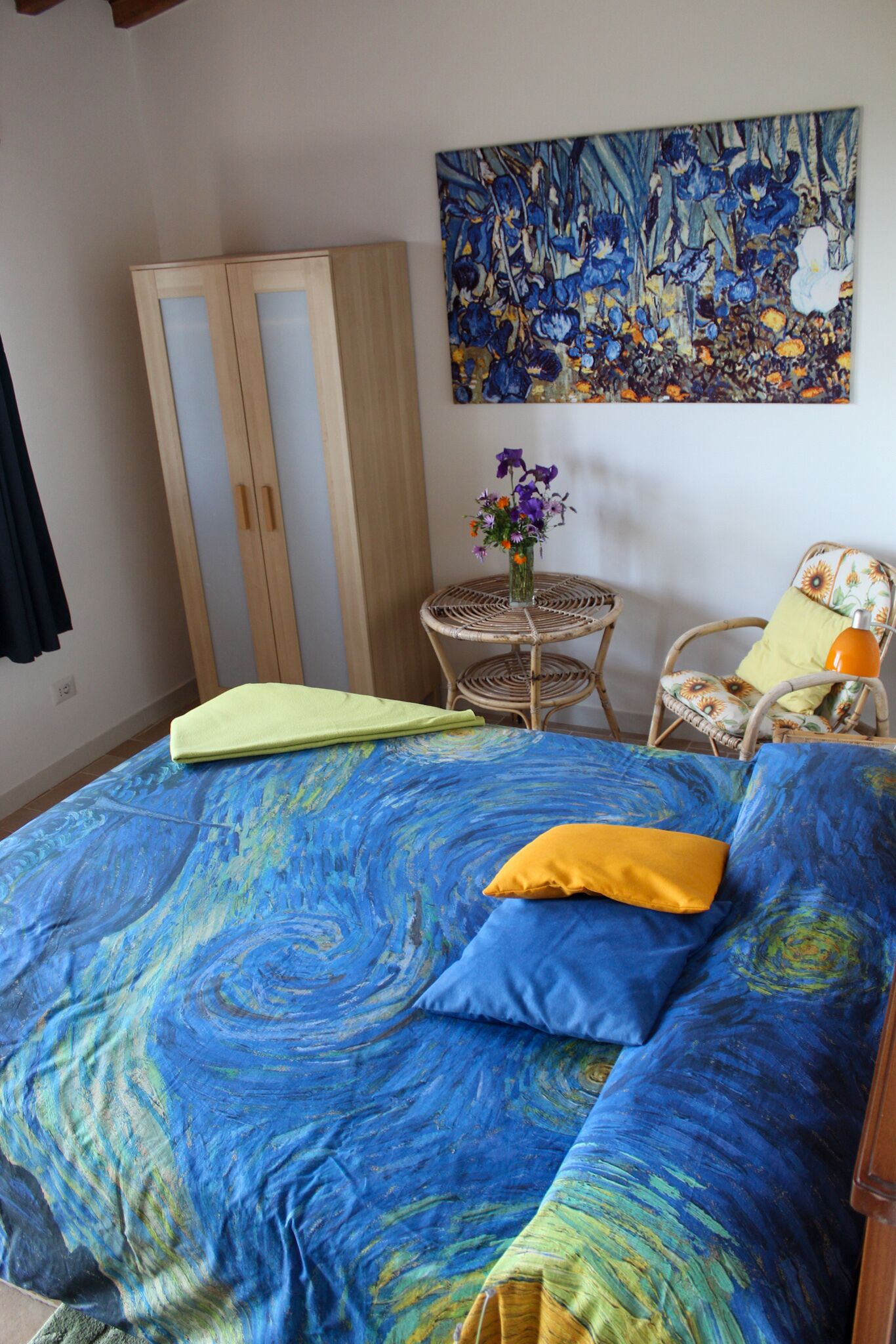 Un dormitorio con cama, armario, silla, mesa y un cuadro en la pared.