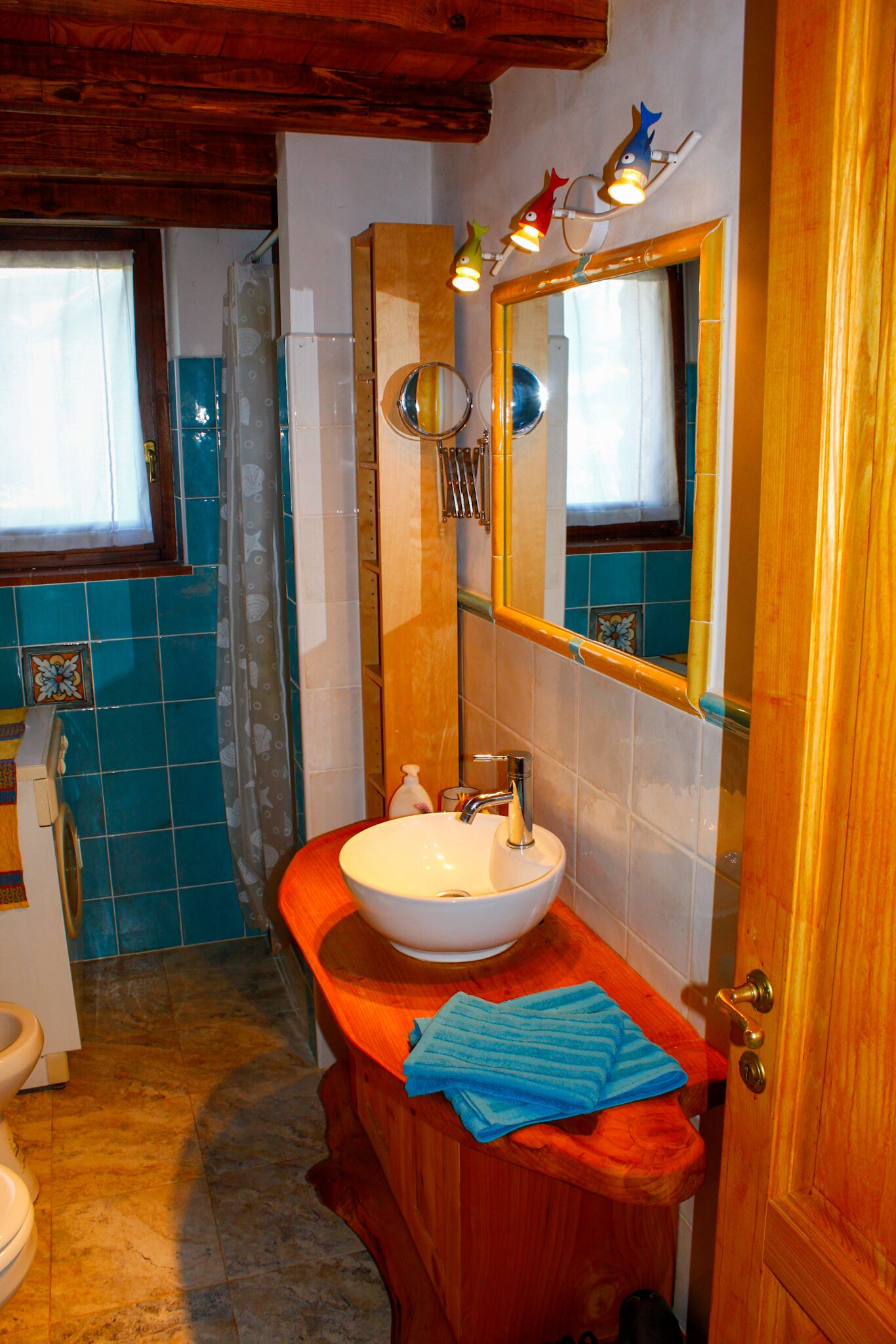A bathroom with a wooden vanity, a white sink, and a mirror.