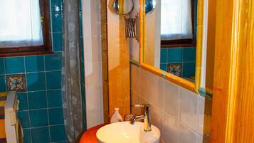 A bathroom with a wooden vanity, a white sink, and a mirror.
