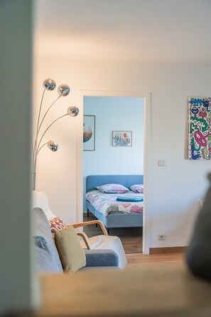 A room with a bed, a chair, a floor lamp, and a wall with a colorful painting. - L'Obernoi, located in a private residence not far from the city center (Obernai)