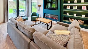 Ein modernes Wohnzimmer mit einer Couch, einem Couchtisch, einem Fernseher und einem Kamin.