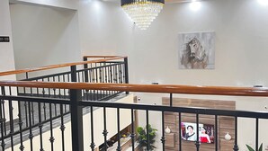 A hotel lobby with a marble staircase, a chandelier, and a painting of a horse. - De Rigg Place Victoria Island  (Lagos)