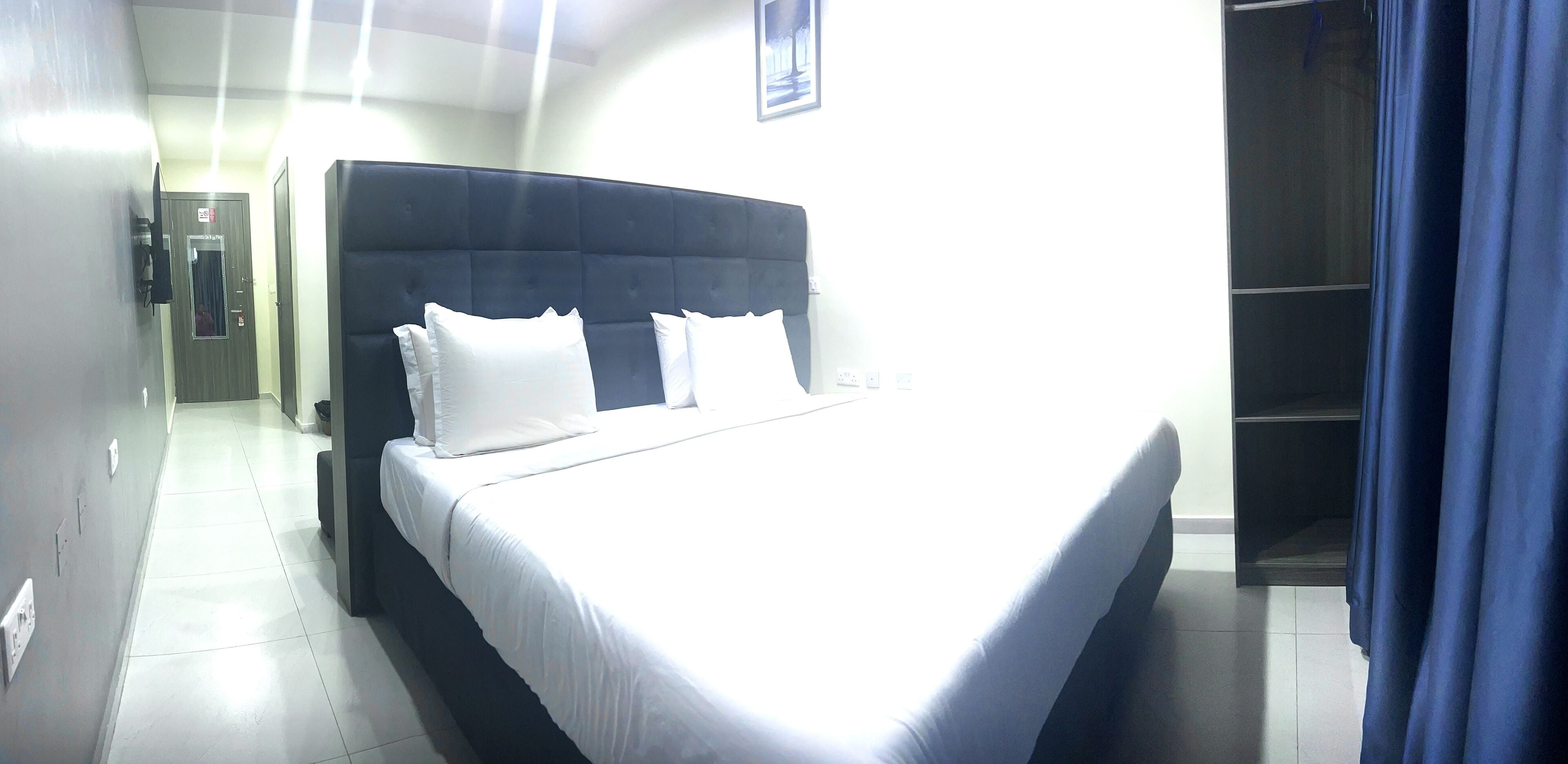 Una habitación de hotel con una cama grande, un armario y un baño a la vista.