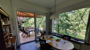 Ein Essbereich mit großem Fenster, Tisch, Stühlen und Bücherregal.