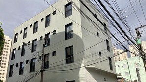 A multi-story building with a flat facade, multiple windows, and visible power lines. - Hotel 34 (Guarulhos)