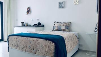 Ein Schlafzimmer mit Bett, einer kleinen Küchenzeile und einem Badezimmer.