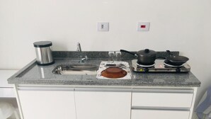 A kitchen with a granite countertop, a stainless steel kettle, a toaster, a frying pan, and a pot on a portable stove. - Hotel 34 (Guarulhos)