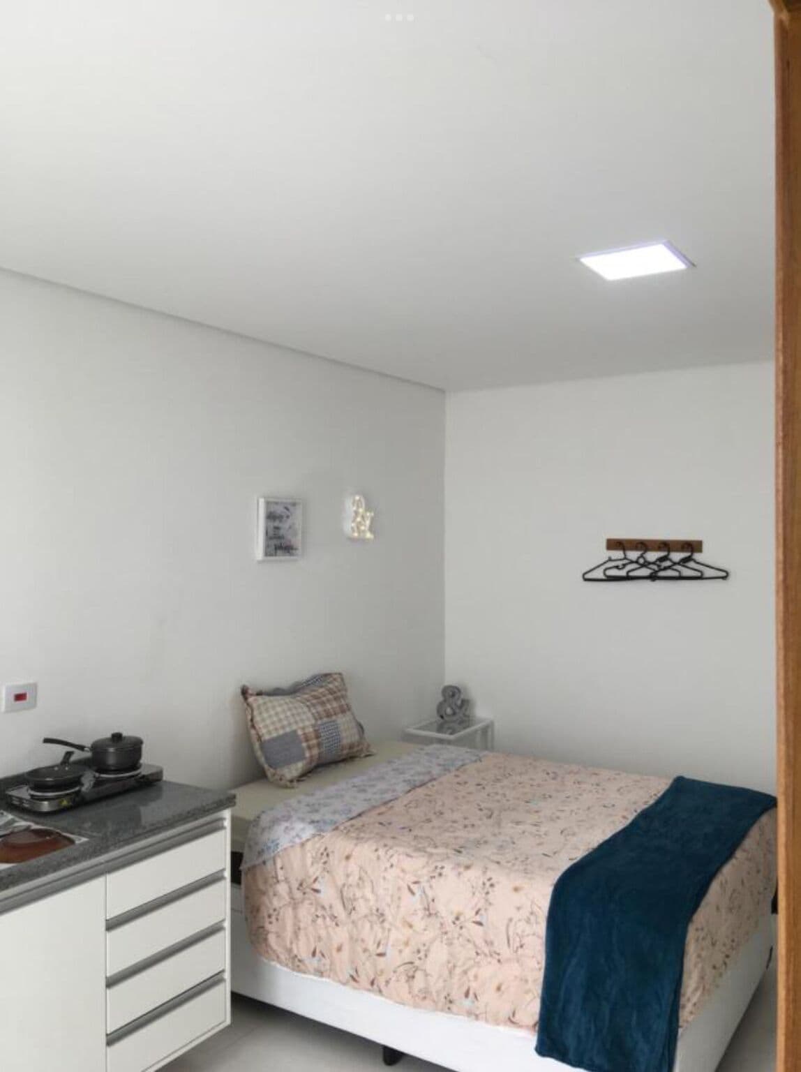 A small, clean room with a bed, a desk, and a small kitchenette.