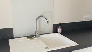 Un baño moderno con un lavamanos blanco, una encimera negra y una toalla colgada en la pared.