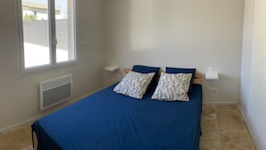 Un dormitorio con cama, ventana, calentador de pared y lámpara en el techo.