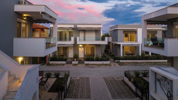 Un moderno complejo residencial con varias edificaciones de dos pisos, un patio central y zonas de estar al aire libre.