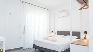 Una habitación de hotel moderna con una cama grande, lámparas de noche, una mesita y un aire acondicionado instalado en el techo.