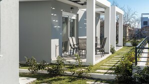 Un patio moderno al aire libre con una zona de estar, un pequeño jardín y una escalera que lleva a un edificio.